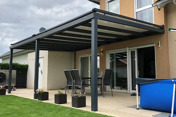 Anthrazitfarbene Terrassenüberdachung mit Sitzgruppe an einem Wohnhaus