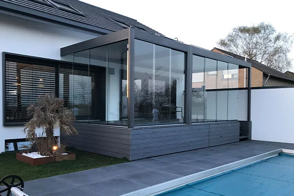 Geschlossener Glasbereich mit anthrazitfarbenem Rahmen neben einer Terrasse